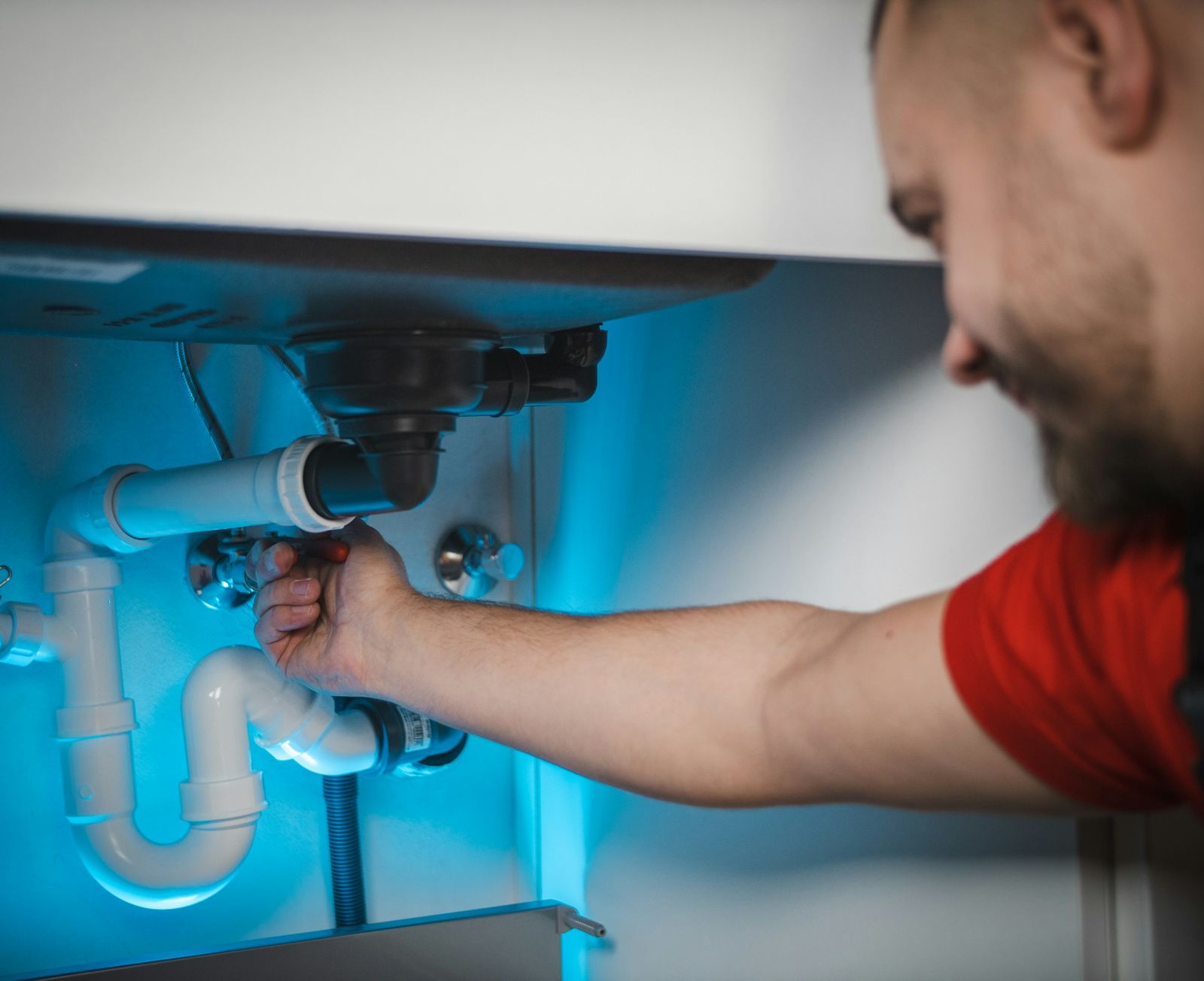 Plumber fitting a sink trap under a bathroom basin